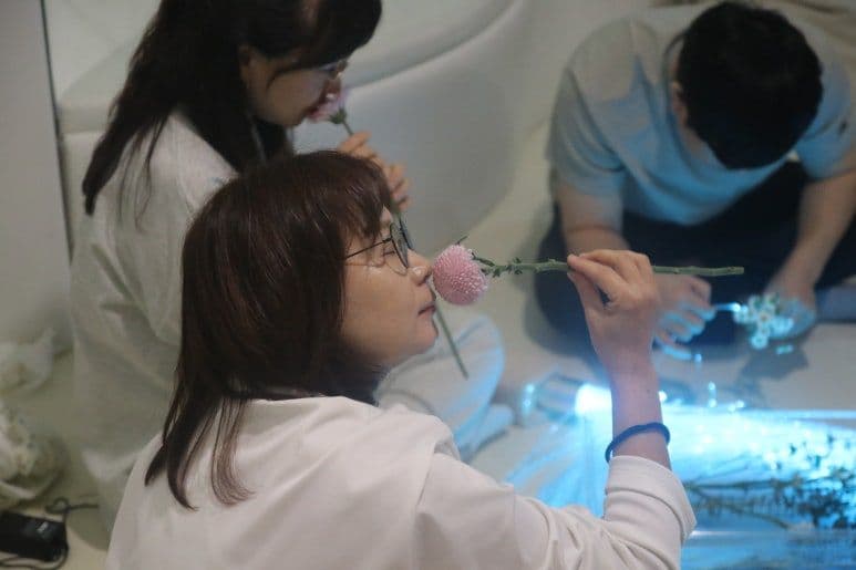 참가자가 생화를 맡으며 후각과 촉각 감각을 탐색하는 모습