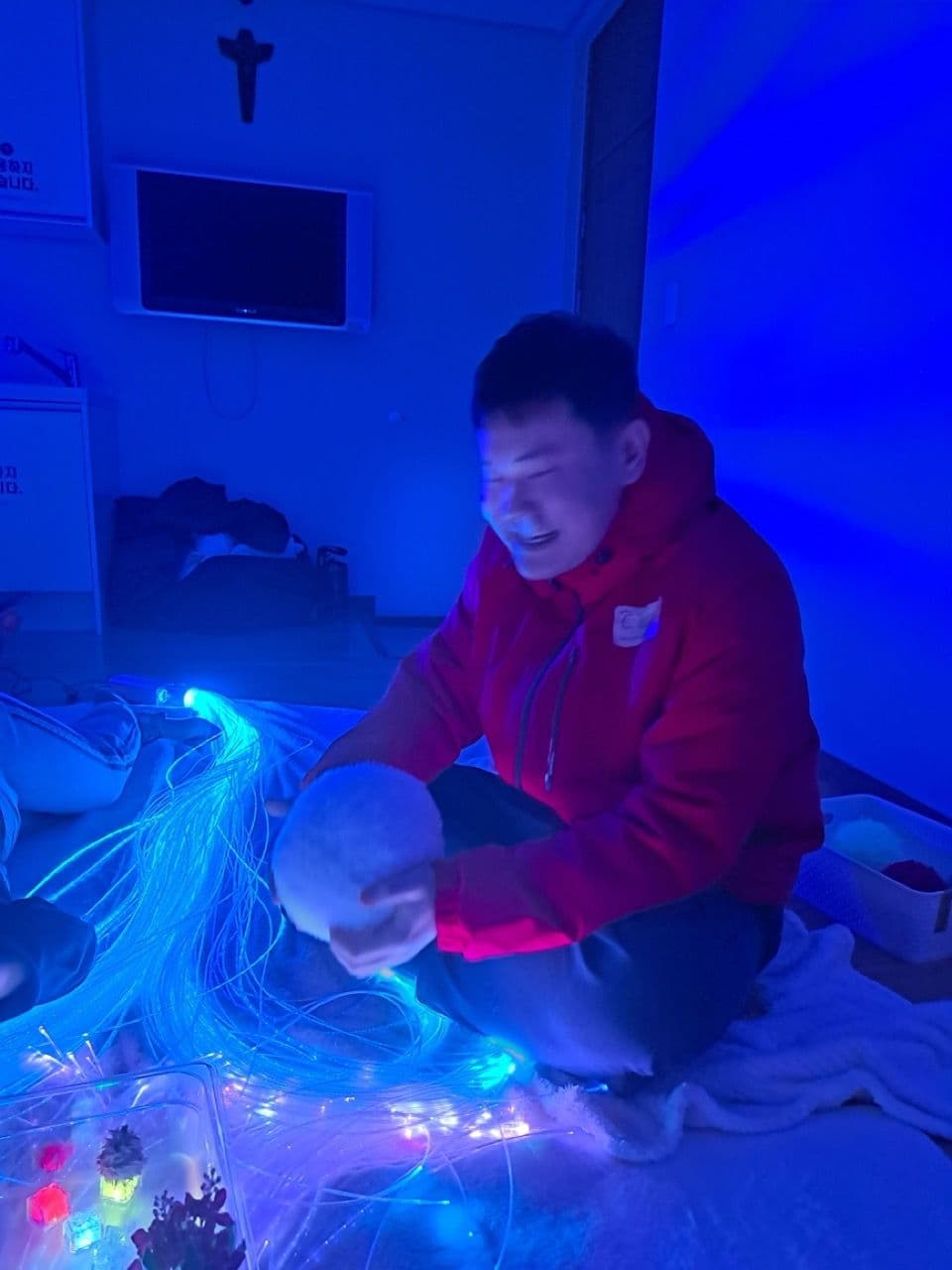 진행자가 이용자와 함께 푸른 광섬유 조명을 만지며 감각 탐색을 돕는 장면