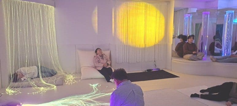 스누젤렌실에서 광섬유와 조명 아래 이완 실습을 하는 참가자들